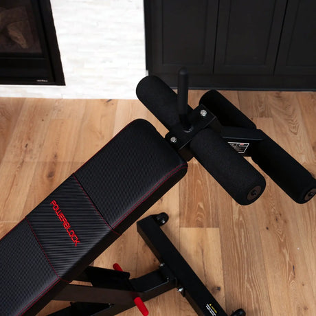 A PowerBlock bench with a sit-up ab and core attachment attached to the back