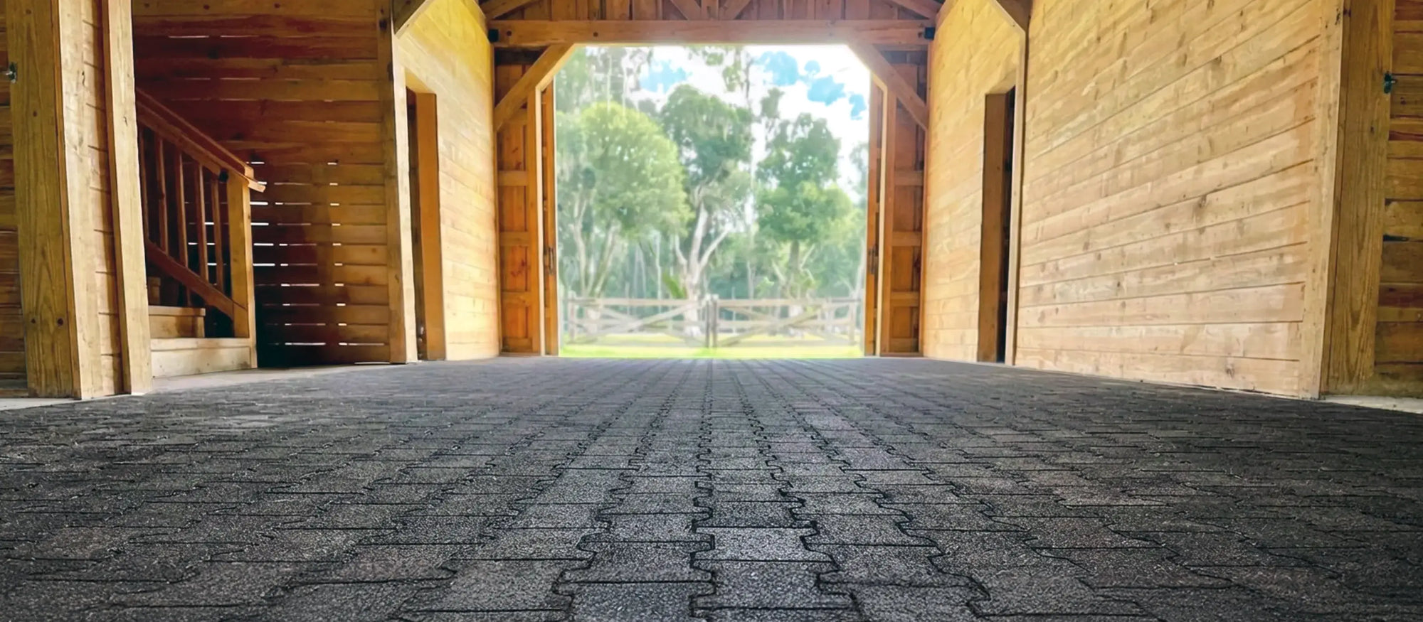 View inside a wooden barn with a black rubber paver floor