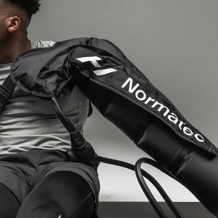 A man wearing an upper body Normatec compression sleeve on his right arm