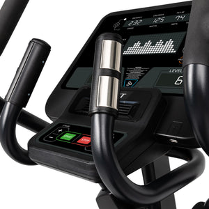 Close-up of the Spirit Fitness CE850 Elliptical's digital display showing fitness metrics like speed, calories, and pulse. Spirit Fitness handlebars with metallic heart rate sensors are visible in the foreground.