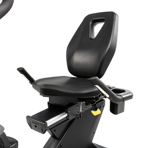 Close-up of the Spirit Fitness CR1000ENT Recumbent Bike seat and backrest assembly, showing the side armrest with cup holder and the sliding rail mechanism used to adjust seat position.