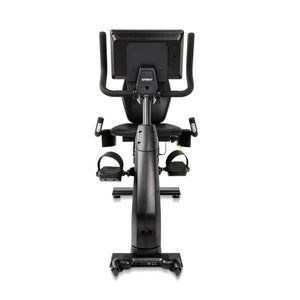 Rear view of the Spirit Fitness CR1000ENT Recumbent Bike showing the back of the console mount, the seat backrest, dual pedals with straps, and the connectivity ports at the base of the frame.