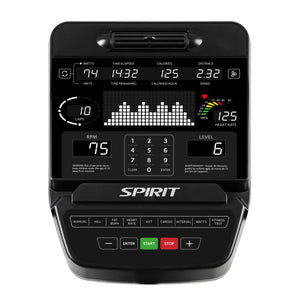 A close-up of the Spirit Fitness CR900 Recumbent Bike control panel shows workout metrics—watts, time, calories, distance, METs, speed, RPM, heart rate, level—with various buttons and a numeric keypad below the screen.