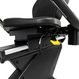 Close-up view of the Spirit Fitness CR900 Recumbent Bike by Spirit Fitness, featuring a black seat with armrests, a yellow adjustment lever, and a sliding track for precise seat positioning.