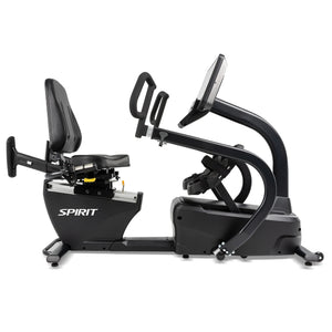 The Spirit Fitness CRS800S Recumbent Seated Stepper is a black exercise bike with a large cushioned seat, backrest, handlebars, pedal straps, and a digital display screen.
