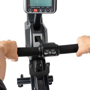 Close-up view of a person’s hands gripping the handlebars of the Spirit Fitness CRW800 Rower, with its central display screen and control buttons visible.