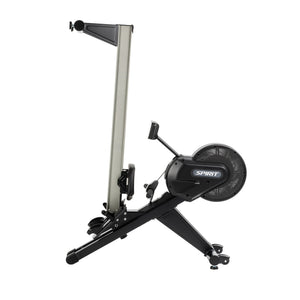 The Spirit Fitness CRW800 Rower by Spirit Fitness is shown in a vertical, upright storage position, featuring a black and silver design with the brand name visible on the flywheel housing.