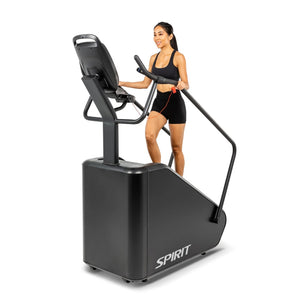 A woman using the Spirit Fitness CSC880 Stair Climber from a front-angle view, hand on the center console handrail.