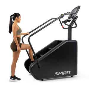 Side view of a woman stepping onto the Spirit Fitness CSC880 Stair Climber, holding the handrail.