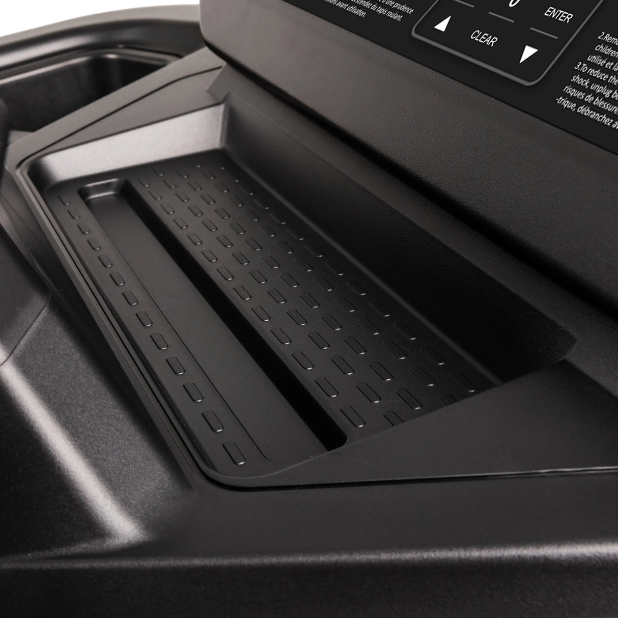 Close-up of a textured black tray with raised edges on the Spirit Fitness CT900 Treadmill, positioned below a control panel featuring buttons and a display screen from Spirit Fitness.