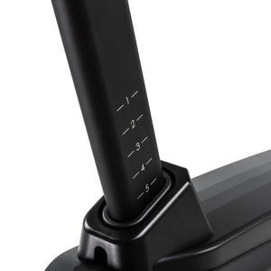 Close-up of the Spirit Fitness CU1000ENT Upright Bike seat post sliding into the frame collar, showing the numbered 1 through 5 height-adjustment markings.