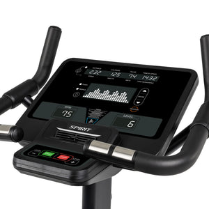 Close-up of a Spirit Fitness CU800 Upright Bike console showing workout stats like distance, calories, pulse, time elapsed, RPM, level readouts, and a workout profile graph with Start/Stop buttons.