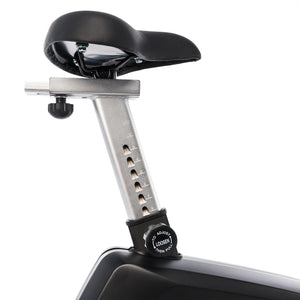Close-up of the Spirit Fitness CU800ENT Upright Bike's adjustable black seat with a silver seat post, numbered height markings, and a black adjustment knob for easy seat height changes.